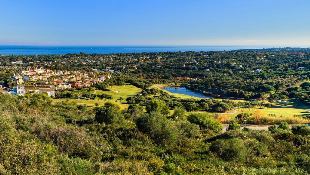 The next image showcases a picturesque scenery abundant with lush green trees, with the city of Sotogrande in the background, highlighting the natural beauty and urban charm of Sotogrande Real Estate.