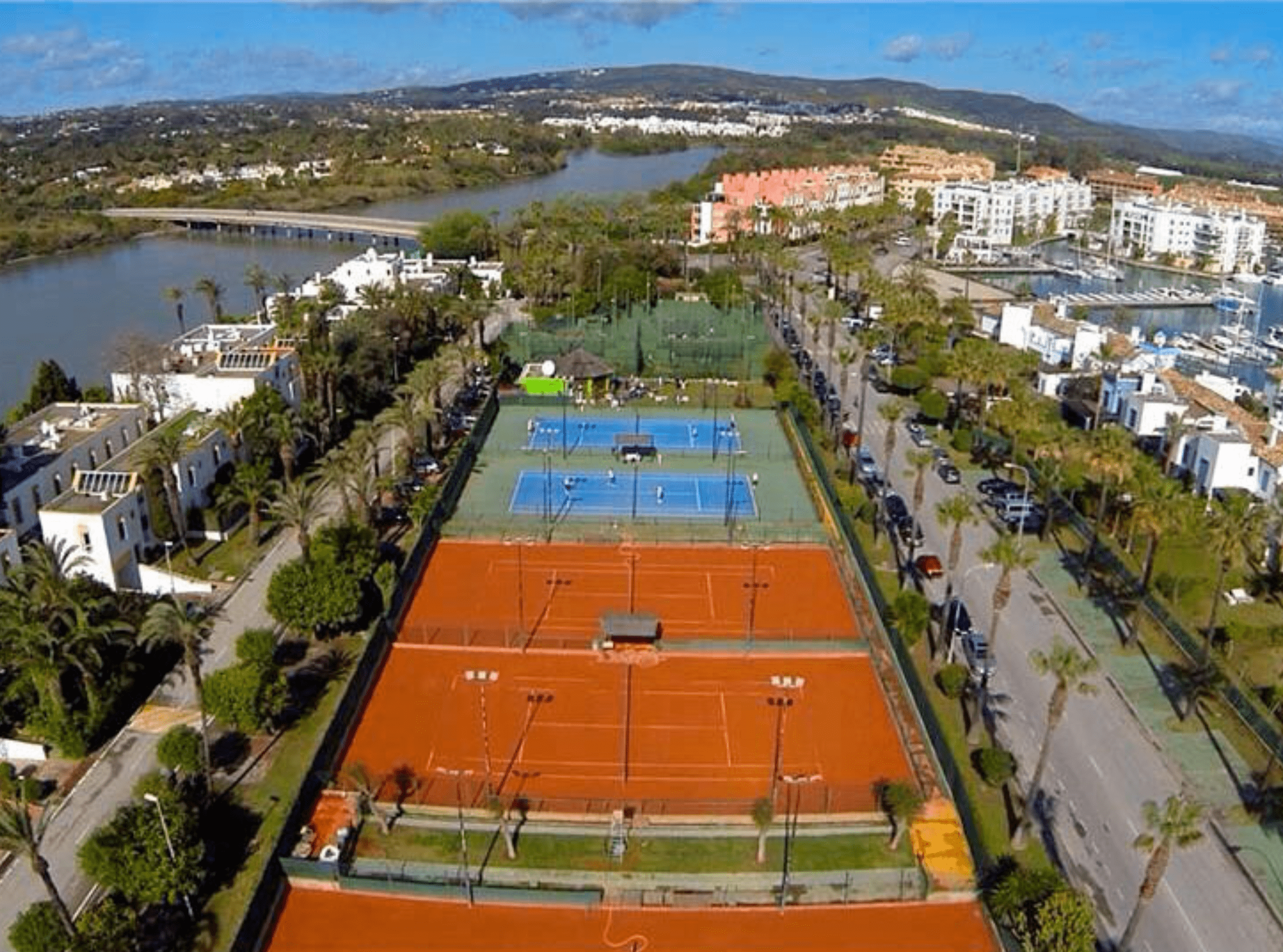 The image depicts a tennis court within the Sotogrande estate, showcasing the premium recreational facilities available to residents and highlighting the lifestyle amenities of this prestigious real estate community.