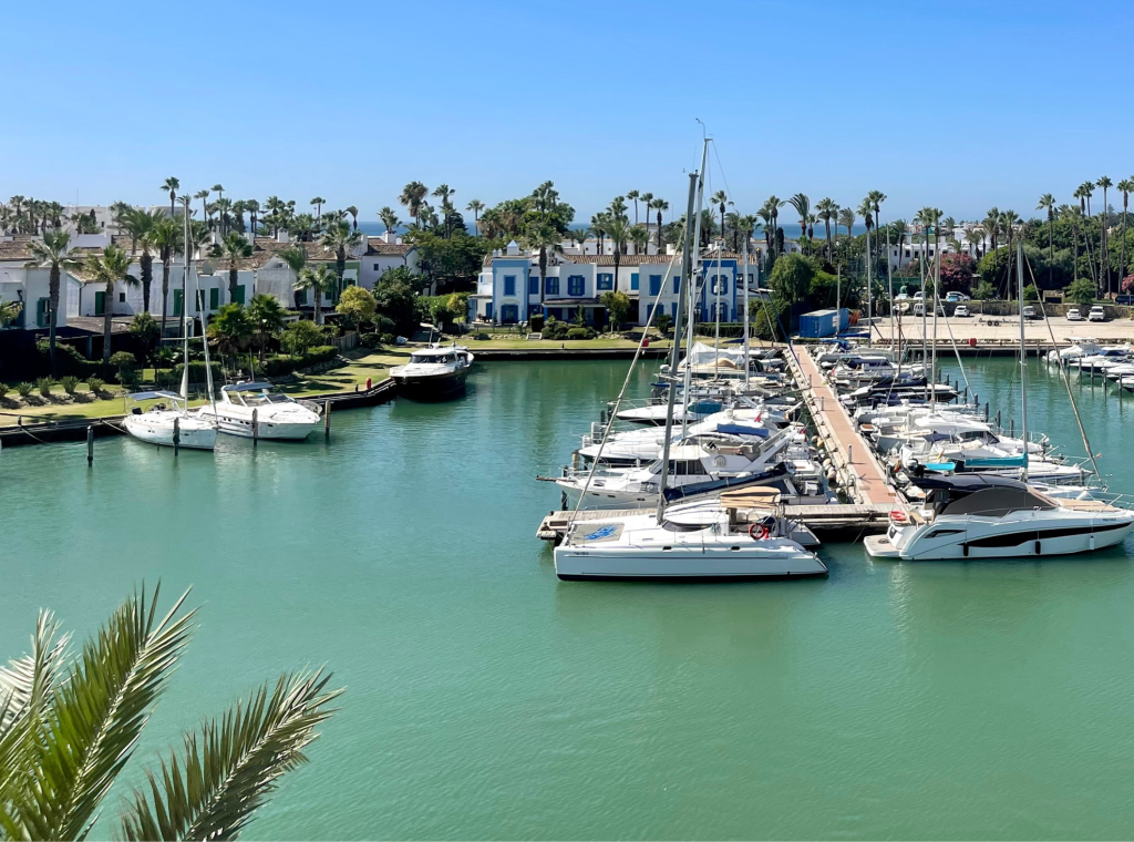 A property located adjacent to a marina, bathed in sunlight on a clear day, exemplifying the prime waterfront real estate offerings in Sotogrande