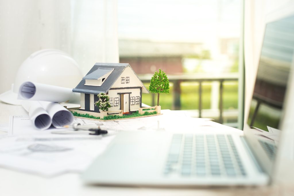 Architectural model of a house with blueprints and laptop representing Sotogrande property development