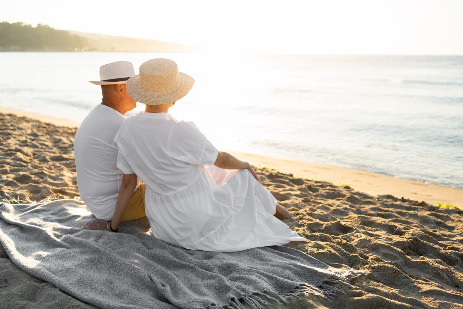 A couple relaxing on a peaceful Mediterranean beach at sunset, reflecting the luxury lifestyle and coastal appeal of Sotogrande real estate.