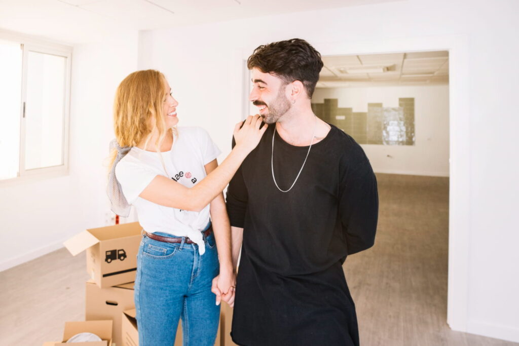Happy couple holding hands in empty apartment with moving boxes, exploring sotogrande property for rent